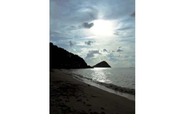 british-virgin-islands-deserted-moody-beach-silhouette-sunlight-breaking-through-clouds-onto-sea