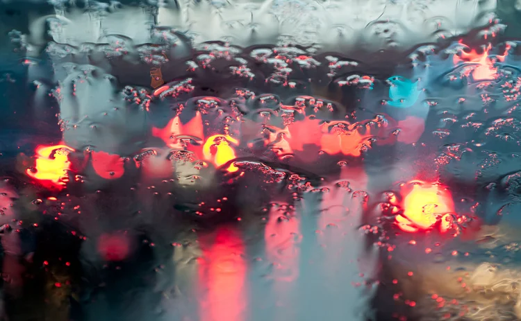 Blurred traffic lights through a rainy windscreen