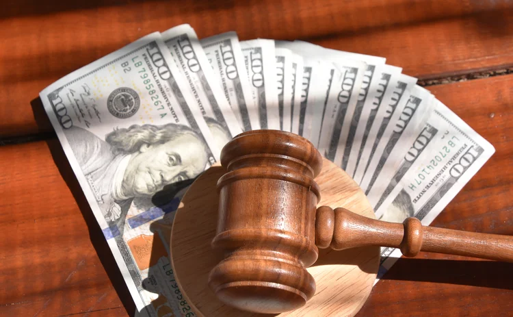 Image of a judge's gavel on a pile of US$100 notes